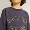 Μπλε-ιώδες φούτερ με την επιγραφή «golden goose» στο μπροστινό μέρος